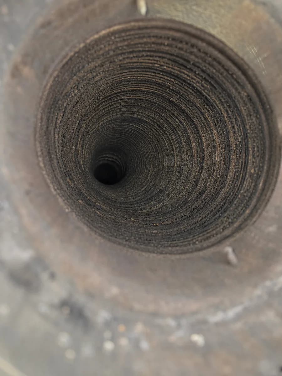 Creosote buildup visible inside a wood stove liner before cleaning