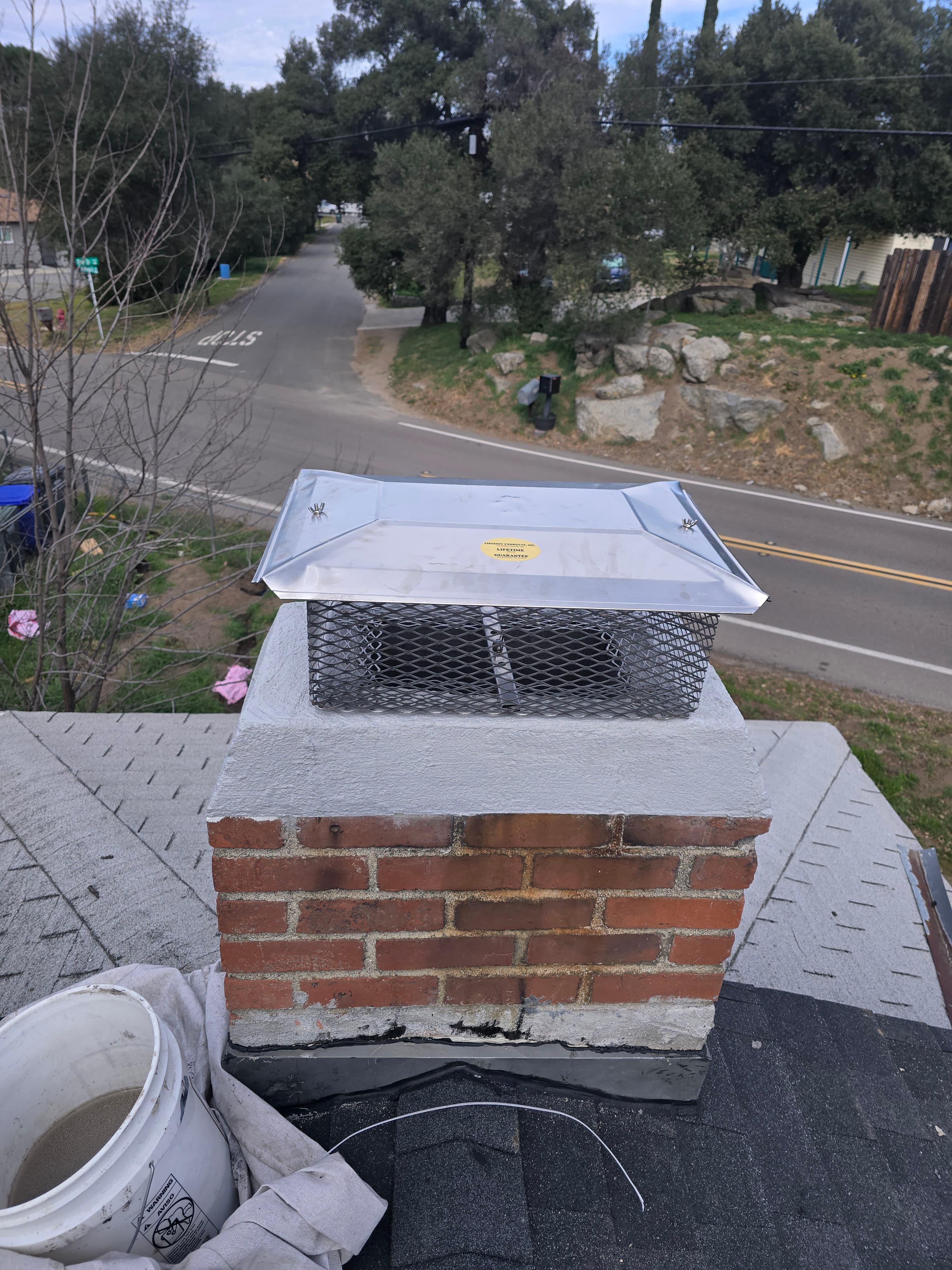 Stainless steel chimney cap seated on a masonry chimney flue tile
